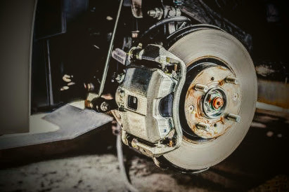 car brake pad and rotor with the wheel removed in an auto repair shop